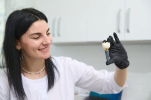 young woman holding dental implant mockup, artificial tooth roots into jaw canal. dental treatment concept.